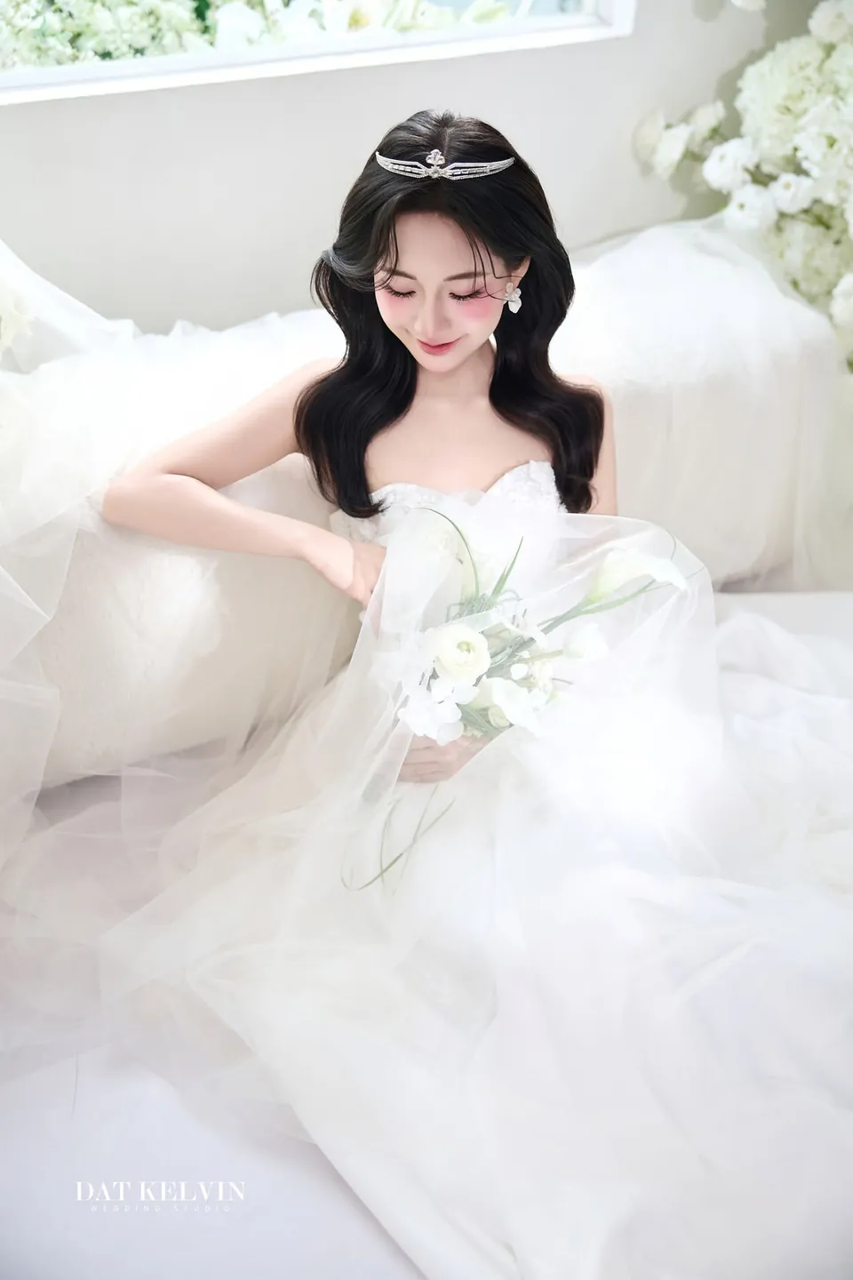 Cô dâu ngồi trên sàn trắng, váy bồng trải rộng