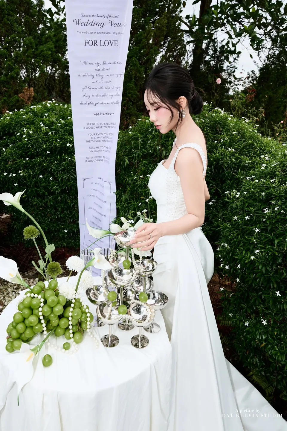 Cô dâu nhìn tháp ly bạc trên bàn tiệc trong vườn