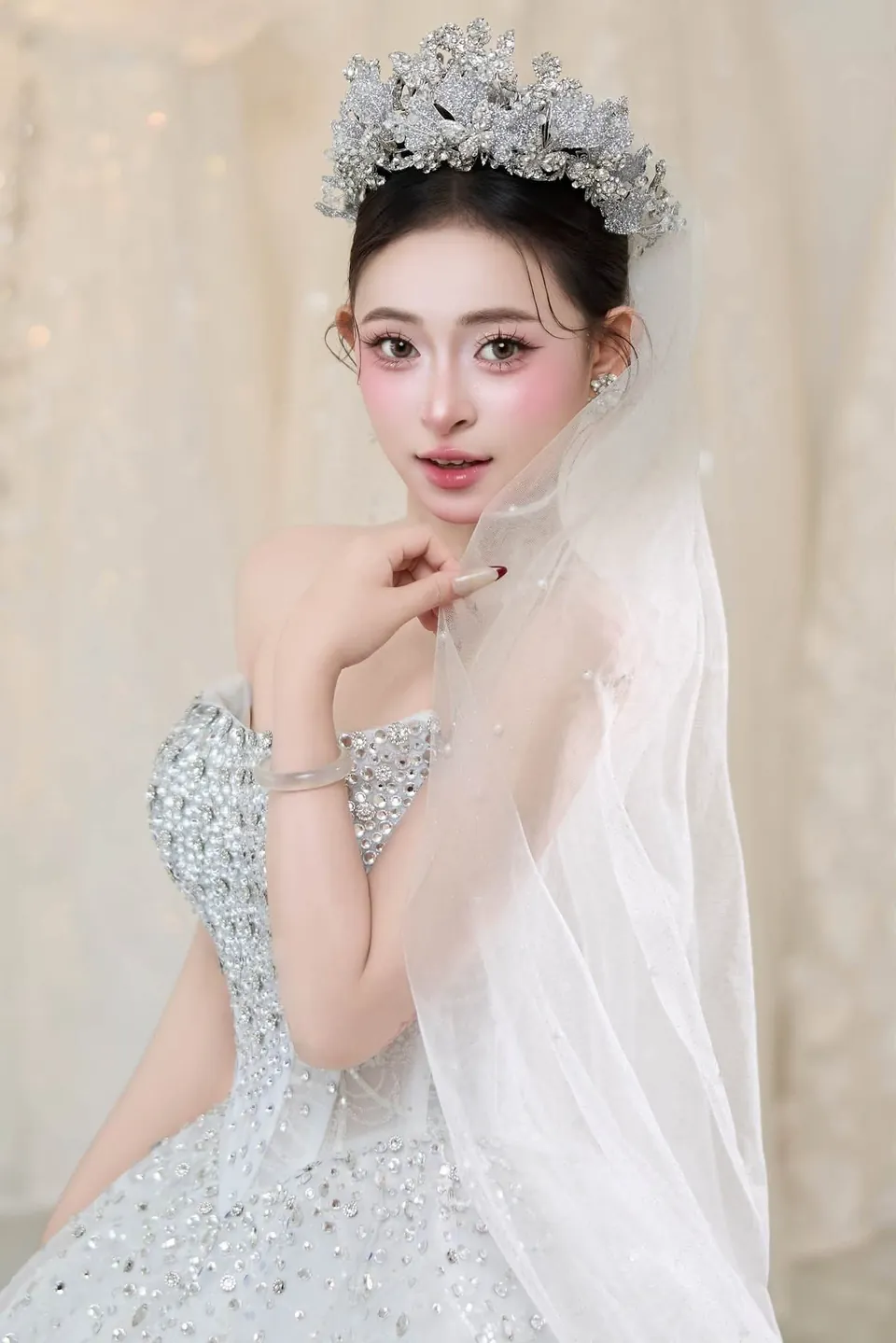 Cô dâu đặt tay lên cằm, đội vương miện và khăn voan