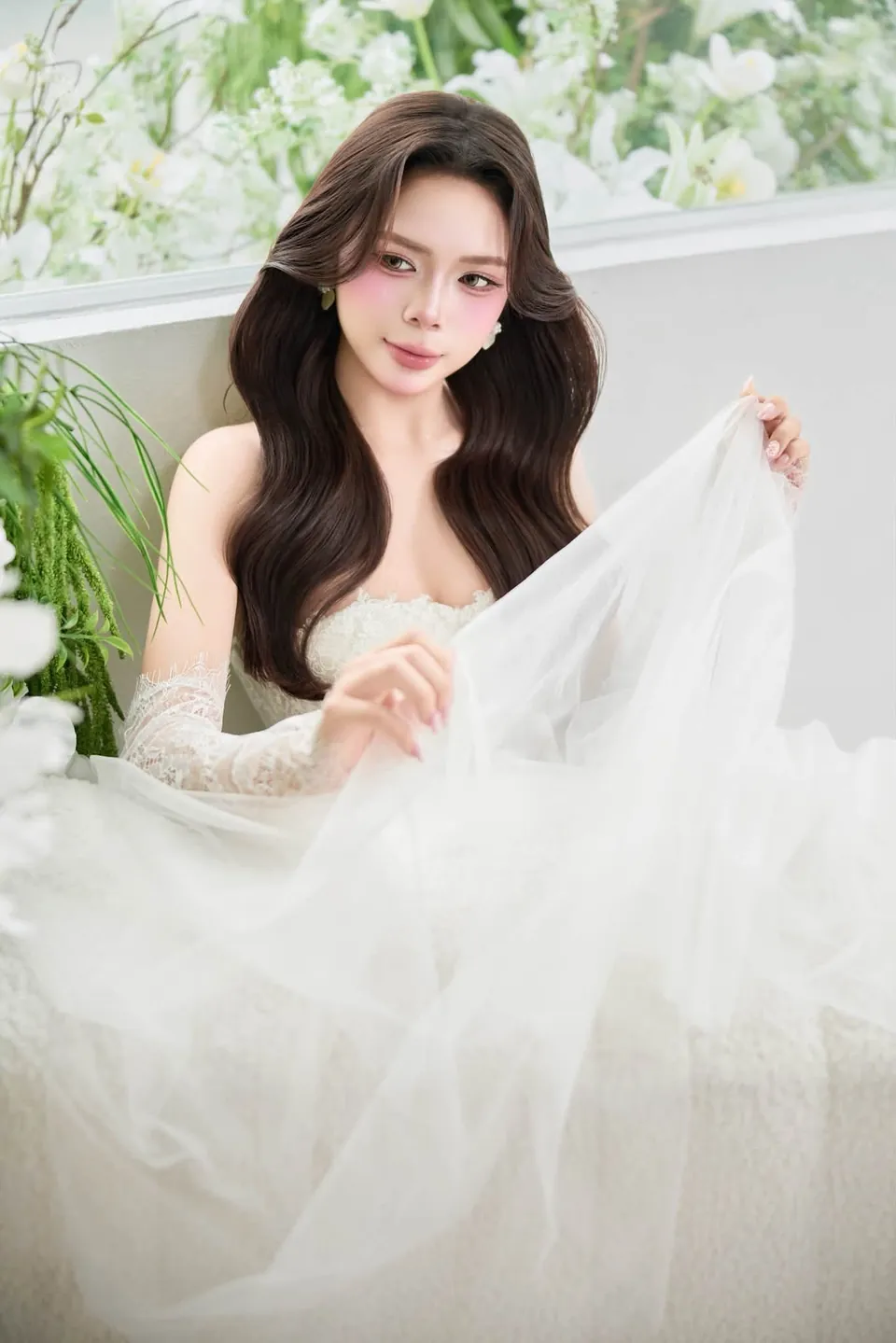 Cô dâu nâng nhẹ tà váy tuyn bên cửa sổ