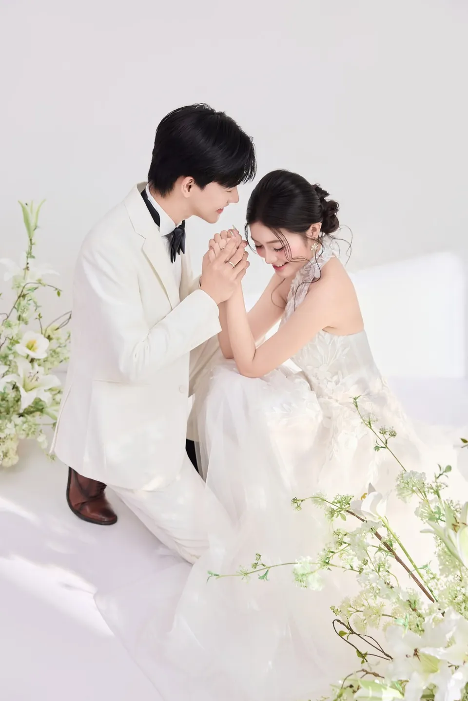 Chú rể quỳ bên cô dâu đang ngồi cười