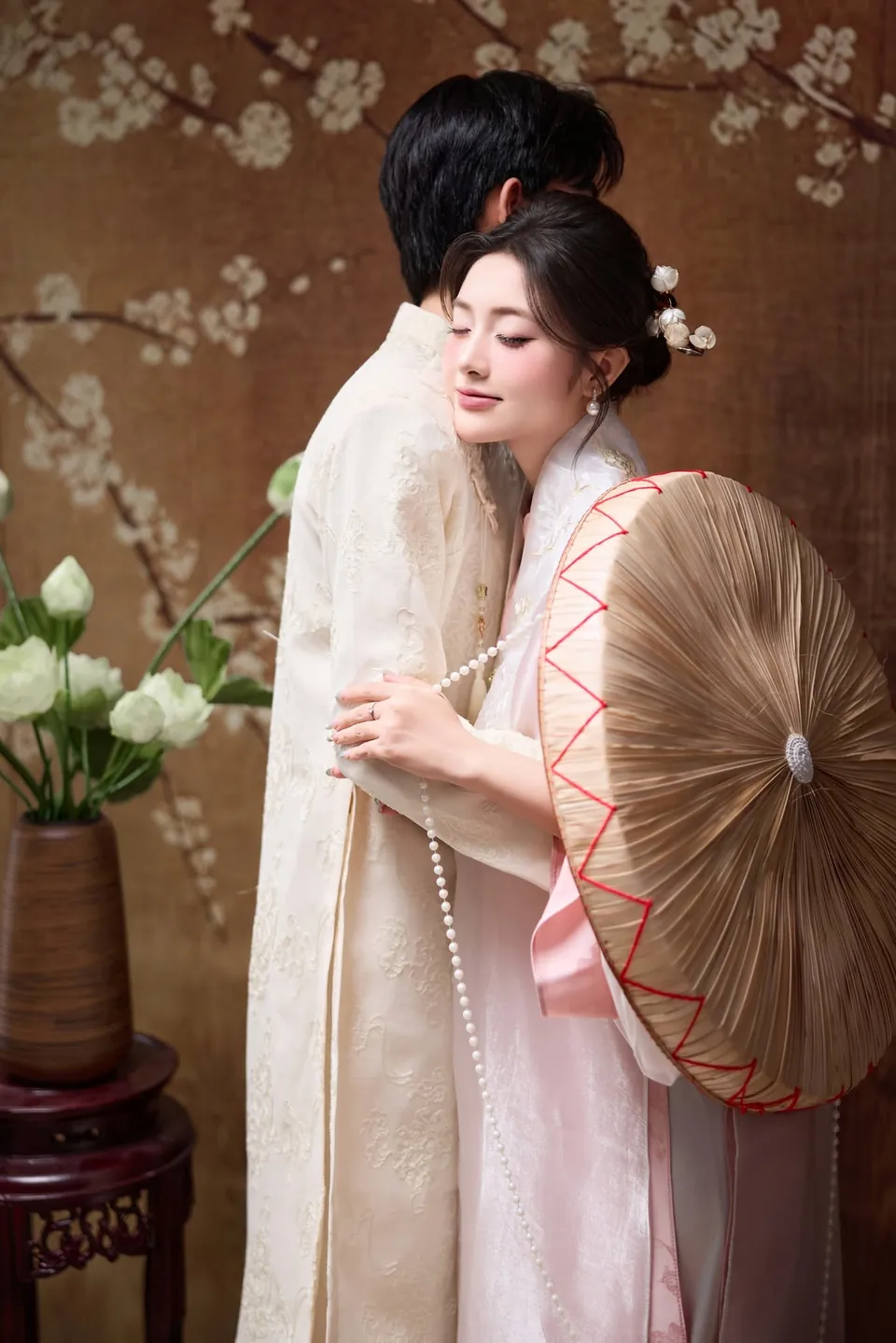 Cô dâu ôm chú rể bên bình hoa trắng