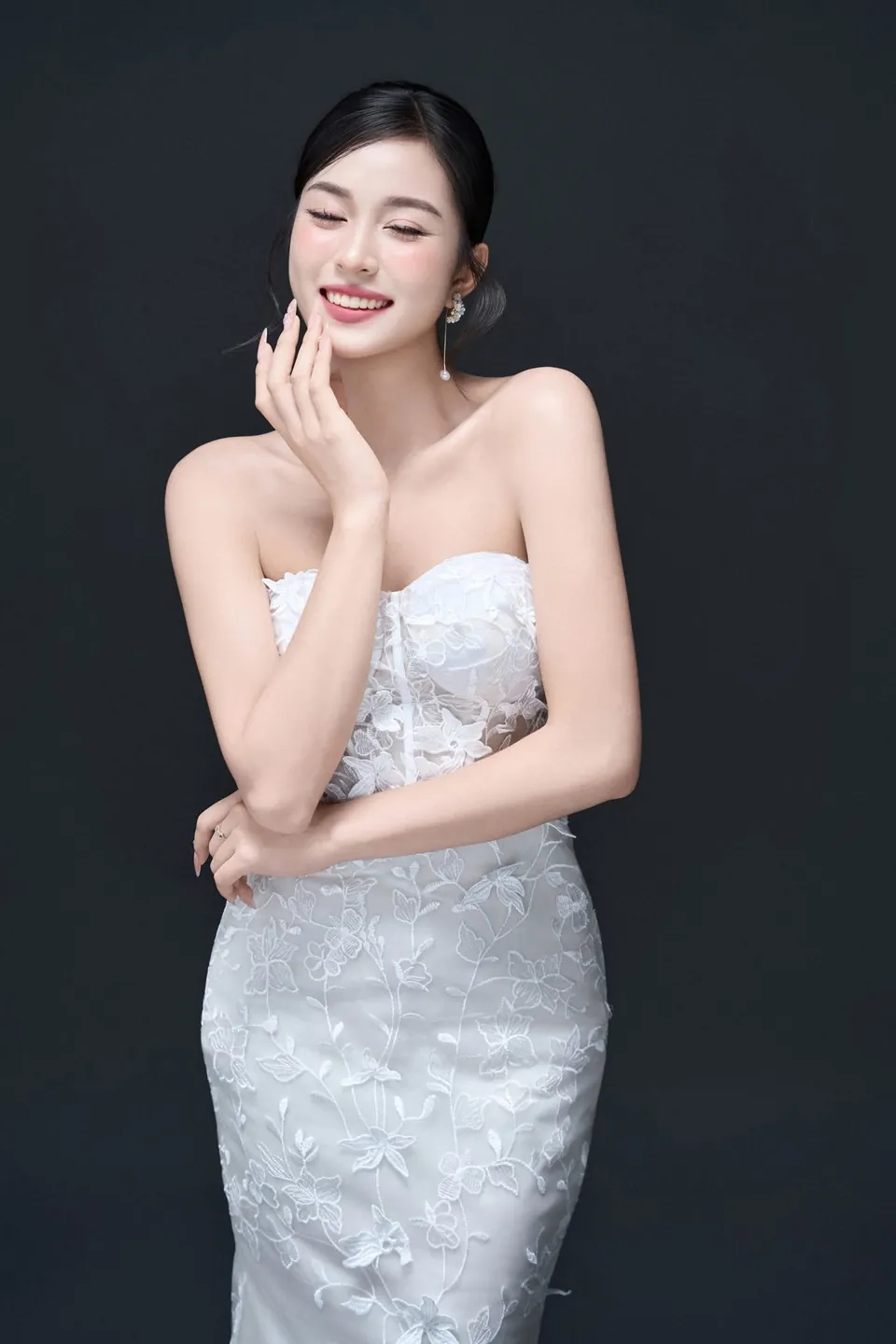 Cô dâu váy ren cúp ngực mỉm cười trên nền xám tối