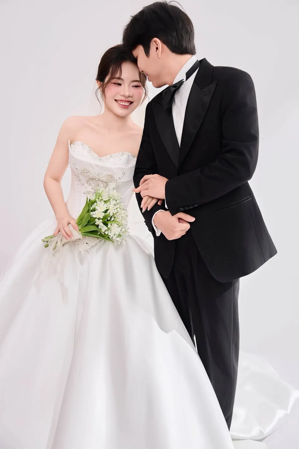 Chú rể vest đen ghé sát cô dâu váy cúp ngực