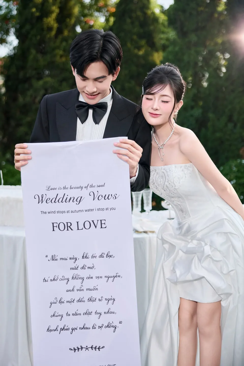 Cô dâu và chú rể cầm cuộn giấy lời thề hôn nhân trong khu vườn