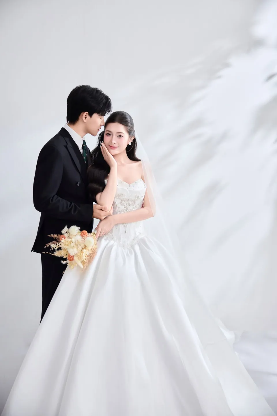 Chú rể ôm cô dâu cầm bó hoa tông cam