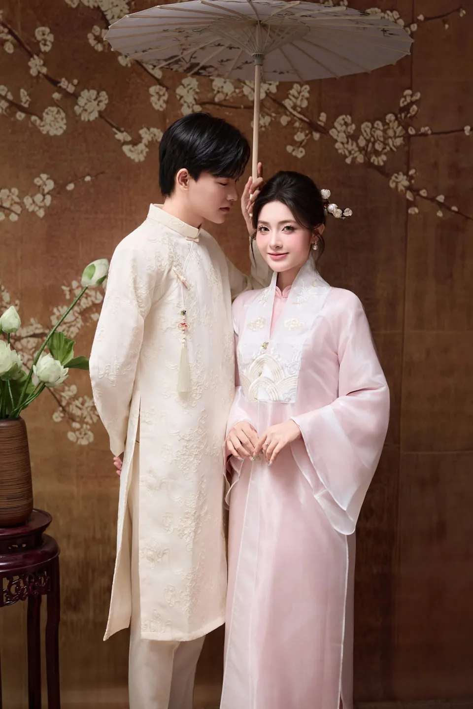 Cặp đôi mặc áo dài đứng dưới chiếc dù giấy trắng