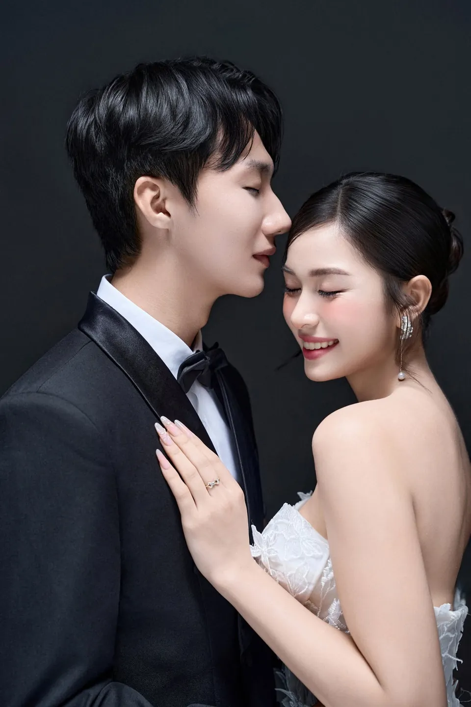 Chú rể kề sát má cô dâu đang nhắm mắt cười