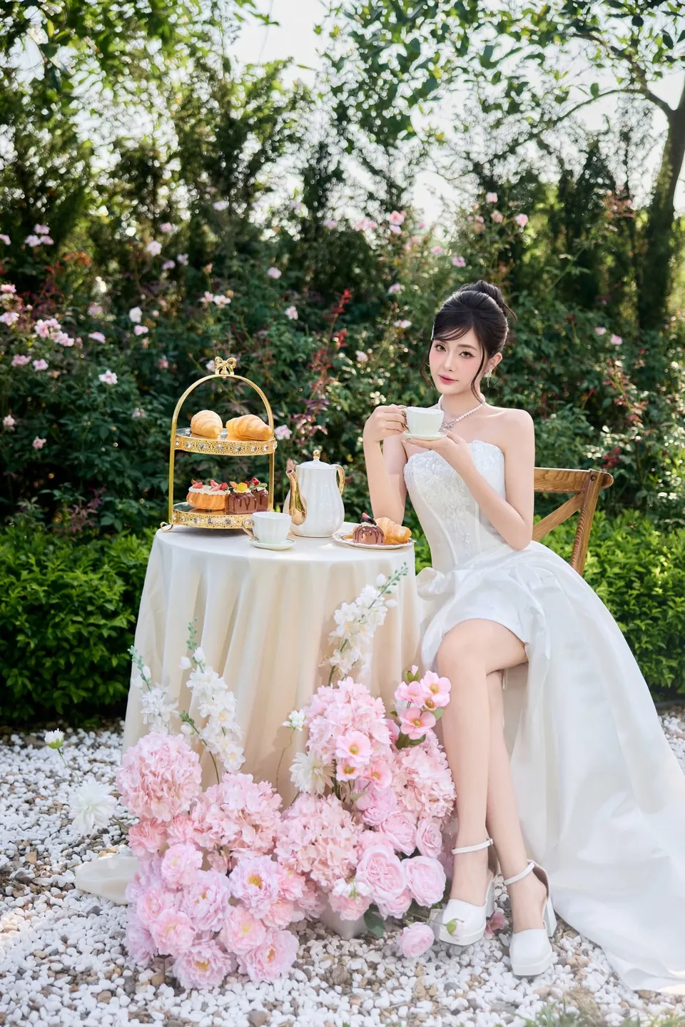 Cô dâu váy cưới ngắn ngồi bên bàn tiệc trà trong vườn