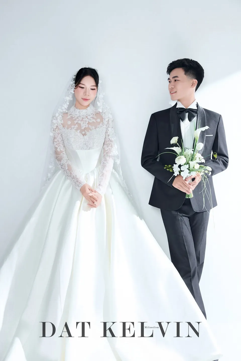 Cô dâu váy cổ cao ren và chú rể cầm hoa loa kèn trắng