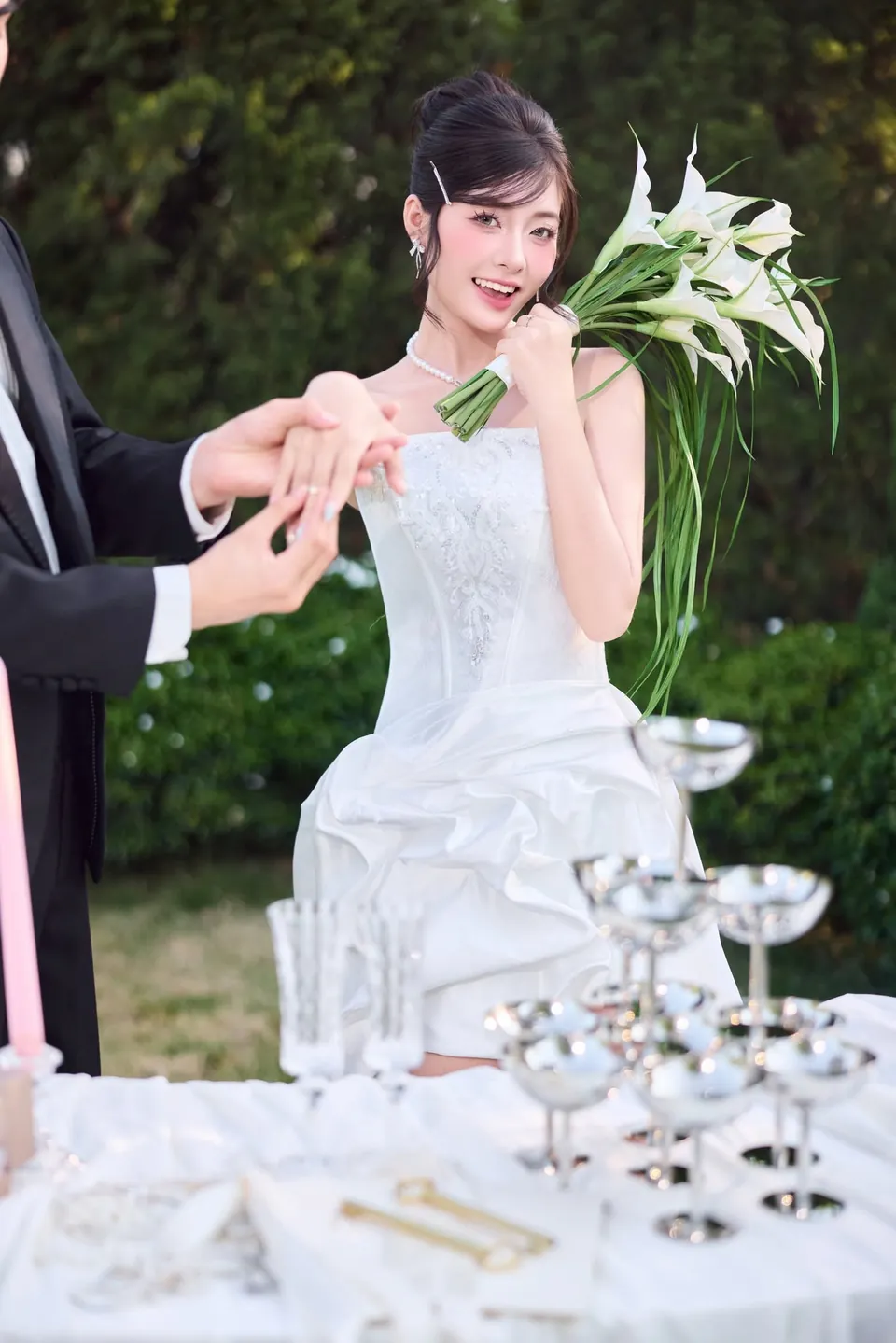 Chú rể đeo nhẫn cho cô dâu cầm bó hoa loa kèn trắng